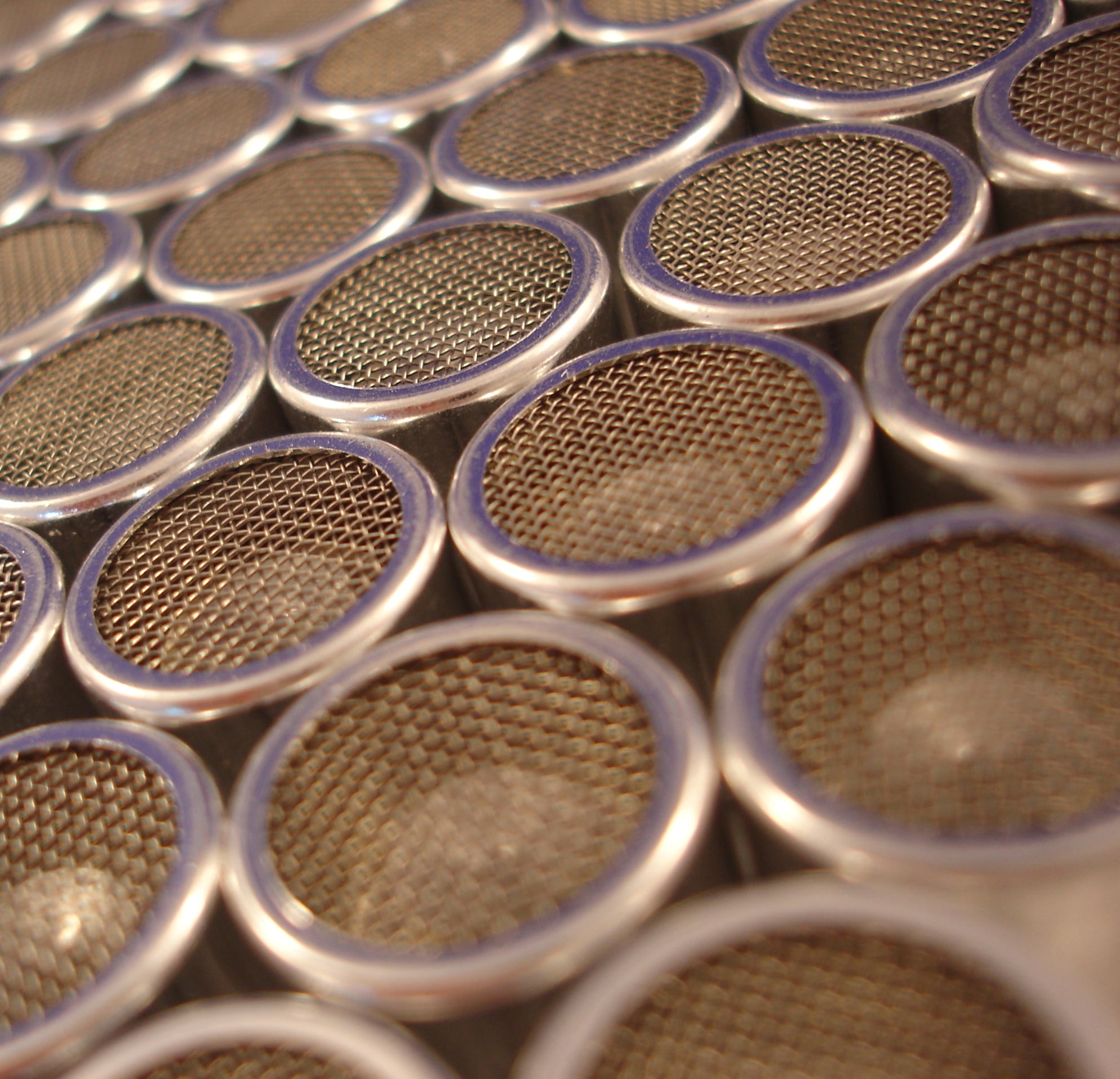 a close up of a bunch of metal cylinders with mesh lids